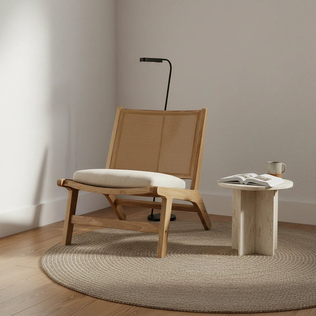 Silla lounge en un rincón de lectura con lámpara de pie, mesa lateral y alfombra de yute