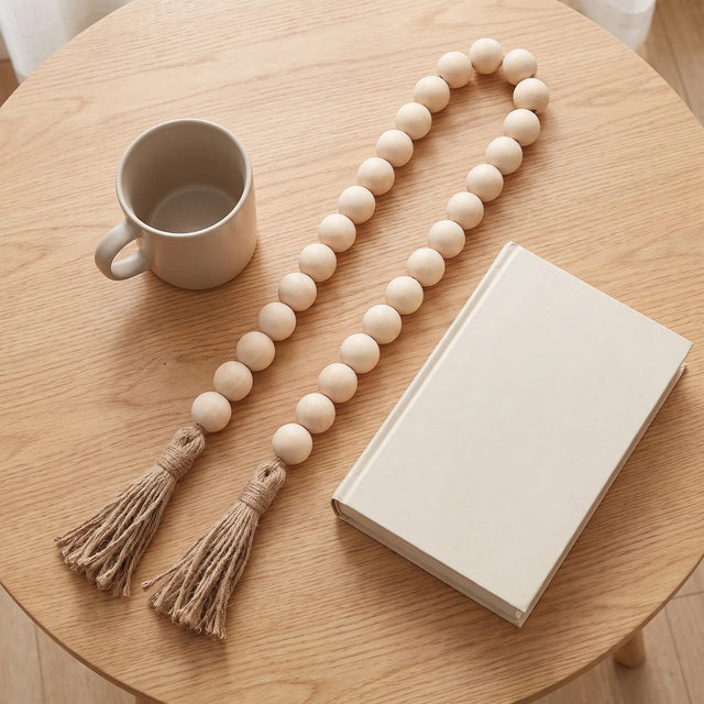 Guirnalda de cuentas de madera extendida junto a una taza y un libro como referencia de escala