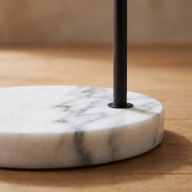 Detalle de la base de mármol blanco con veta gris y del vástago de metal negro