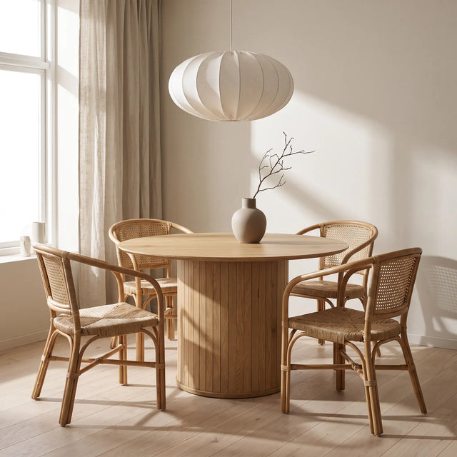 Mesa Koma cerrada en un comedor japandi con cuatro sillas de ratán y lámpara de papel