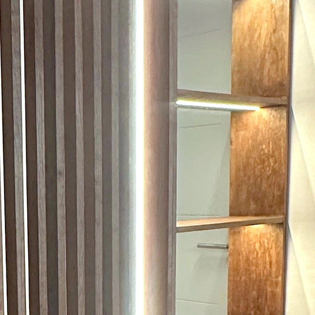 Detalle de la columna de estantería del mueble divisorio con luz indirecta bajo cada repisa