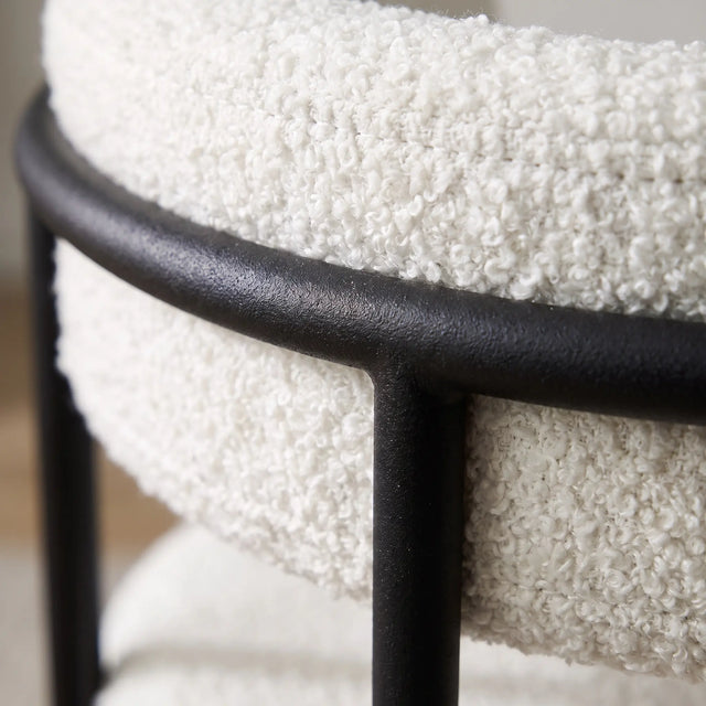 Detalle macro del tejido bouclé blanco contra el fierro negro mate de la Silla Kaia