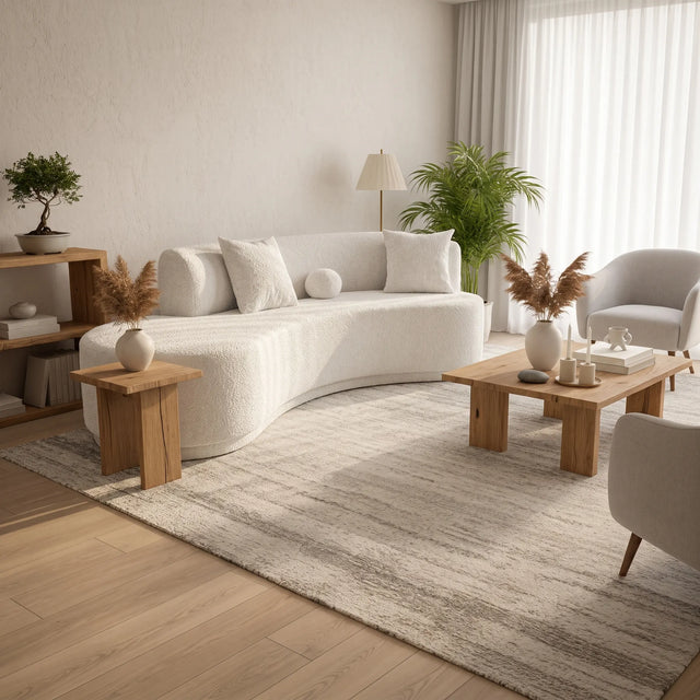 Sofá curvo Amaia visto en ángulo lateral en living con piso de madera clara y alfombra